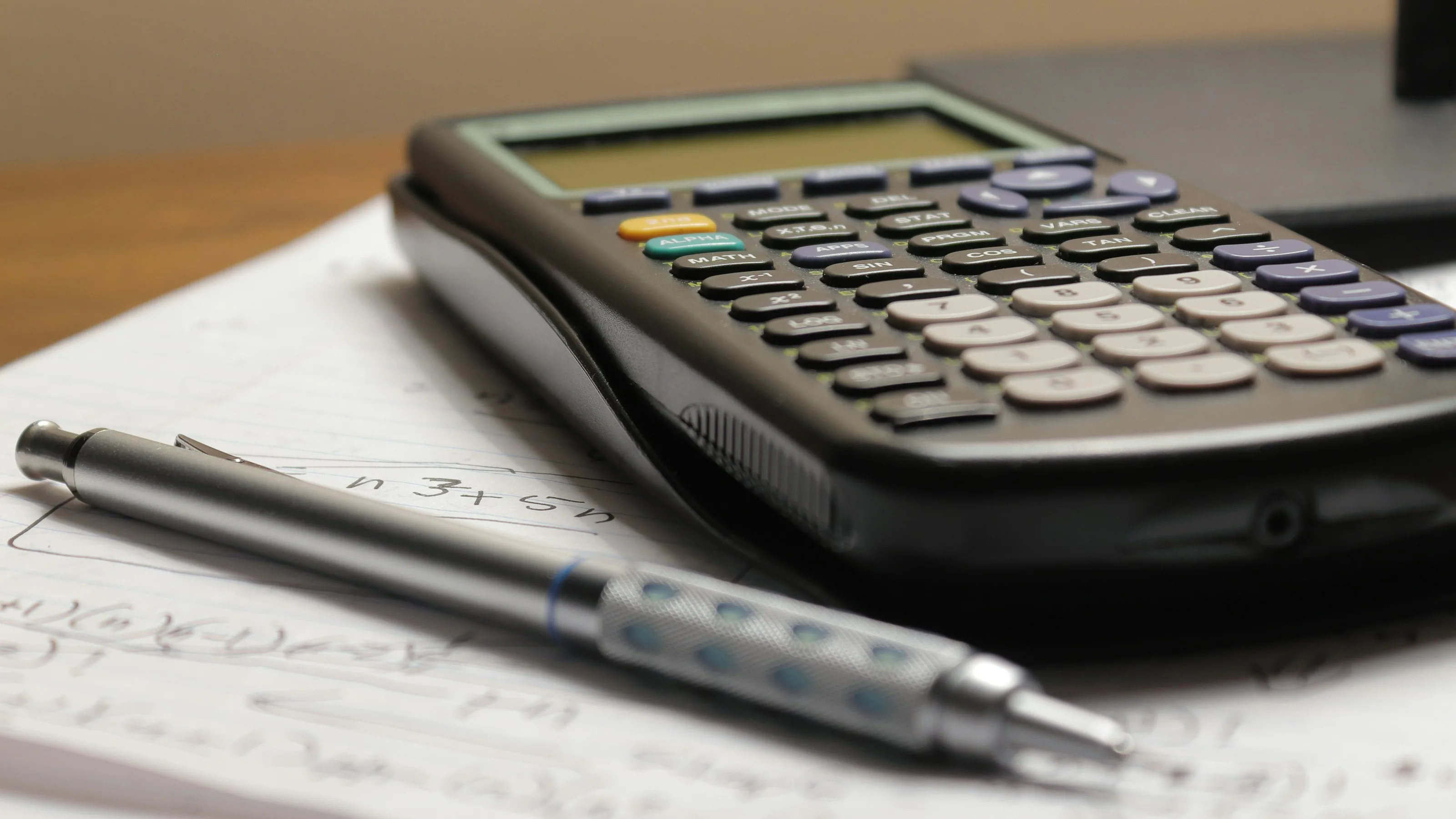 A calculator and notebook open on a desk