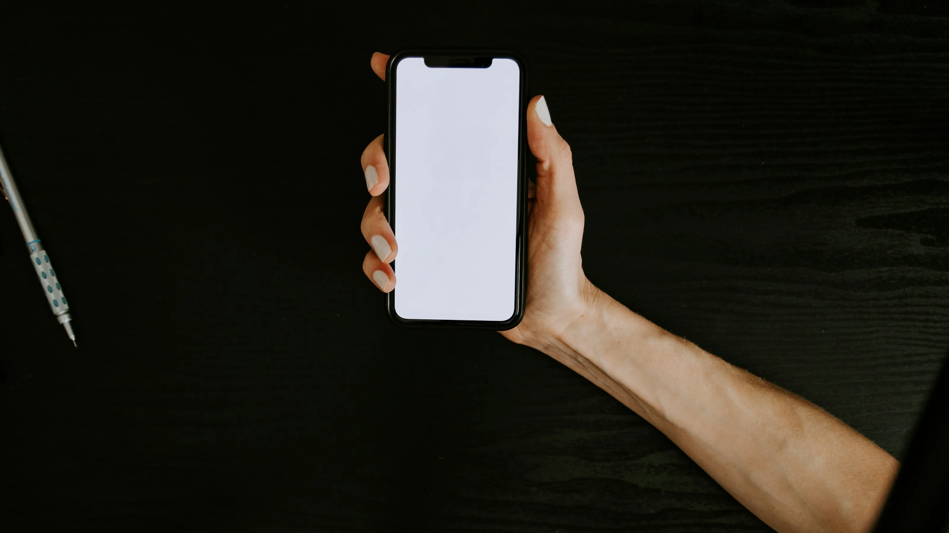 A hand holding a smartphone with a blank screen