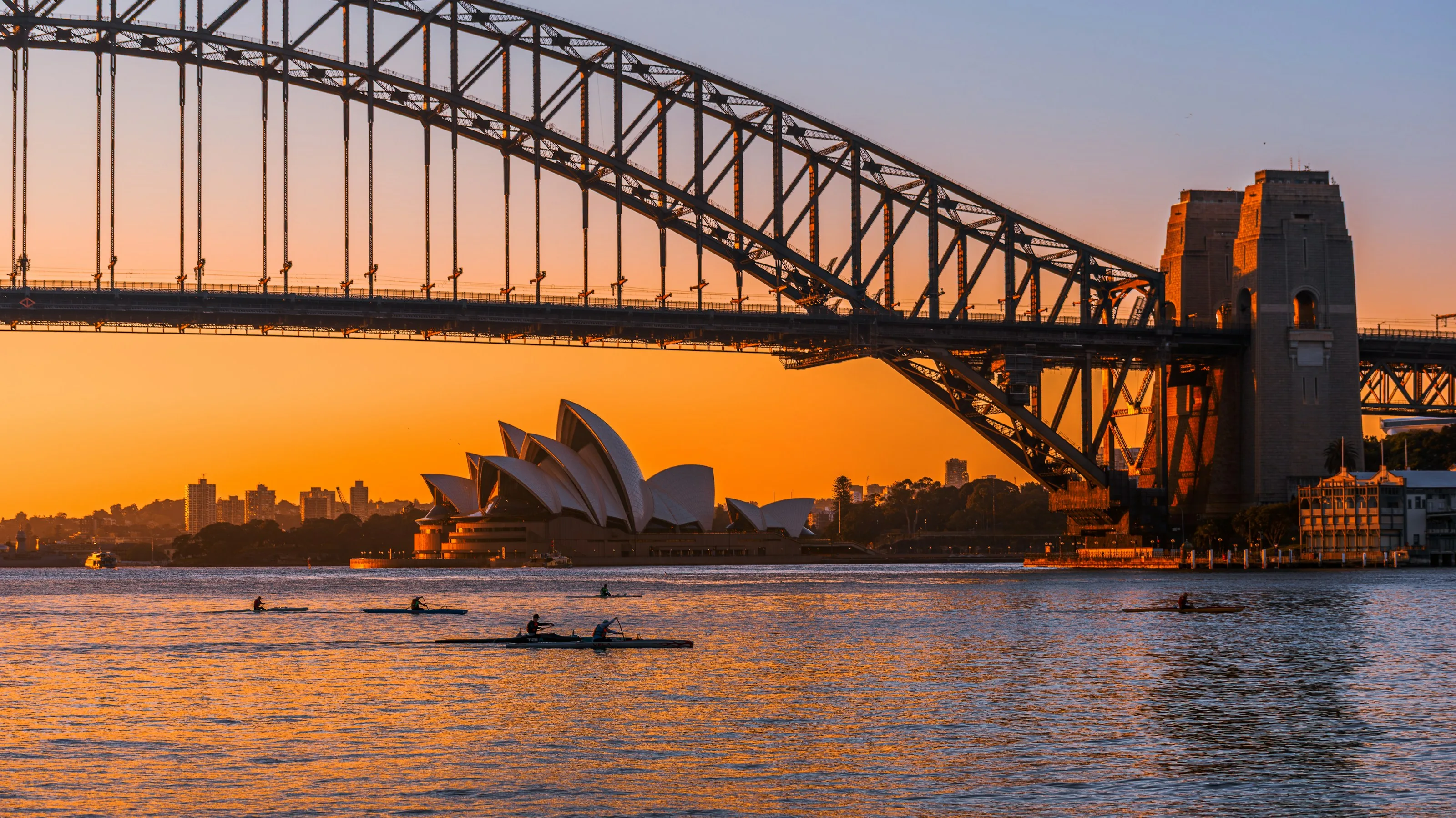 Sydney Harbour Bridge and the Opera House at sunrise, with rowers on the water