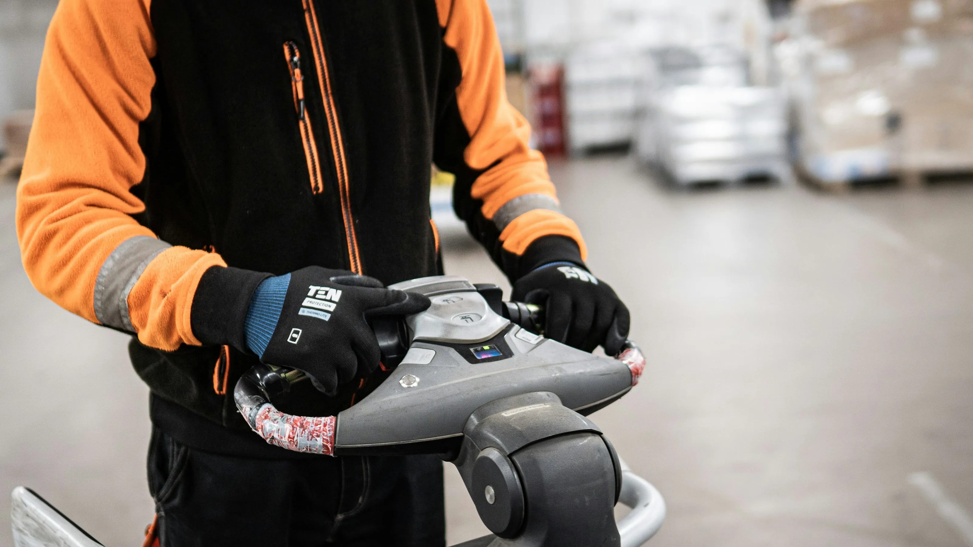 A warehouse worker operating the controls of material handling equipment